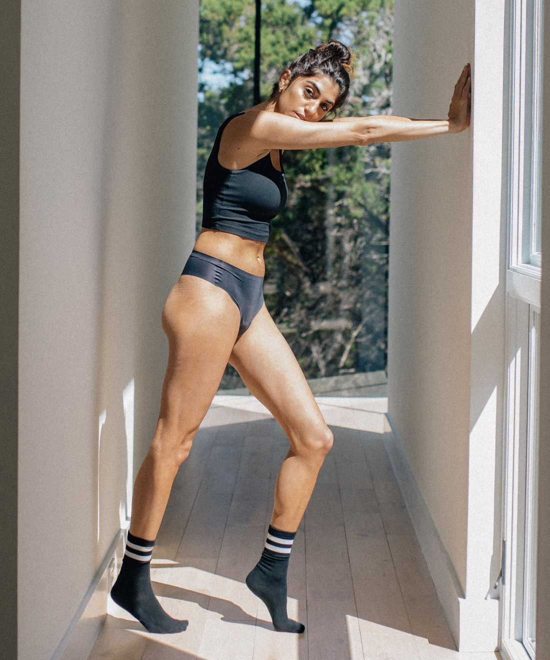 Woman confidently stretching in black camel toe proof thong underwear by Simply Clad — seamless, no front seam, perfect for active movement and everyday comfort.