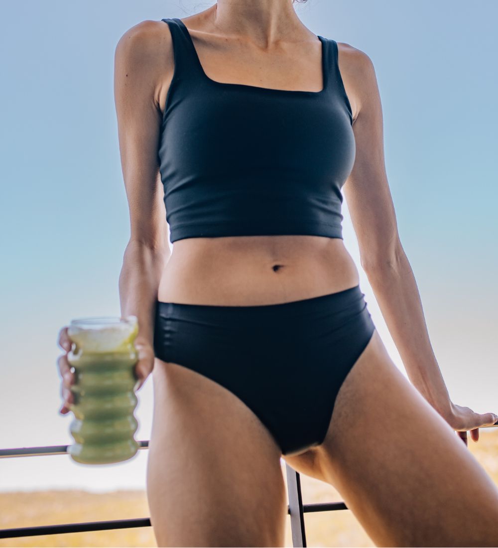 Model in black camel toe proof thong underwear and sports bra mid-motion, showcasing seamless fit and comfort during active movement.