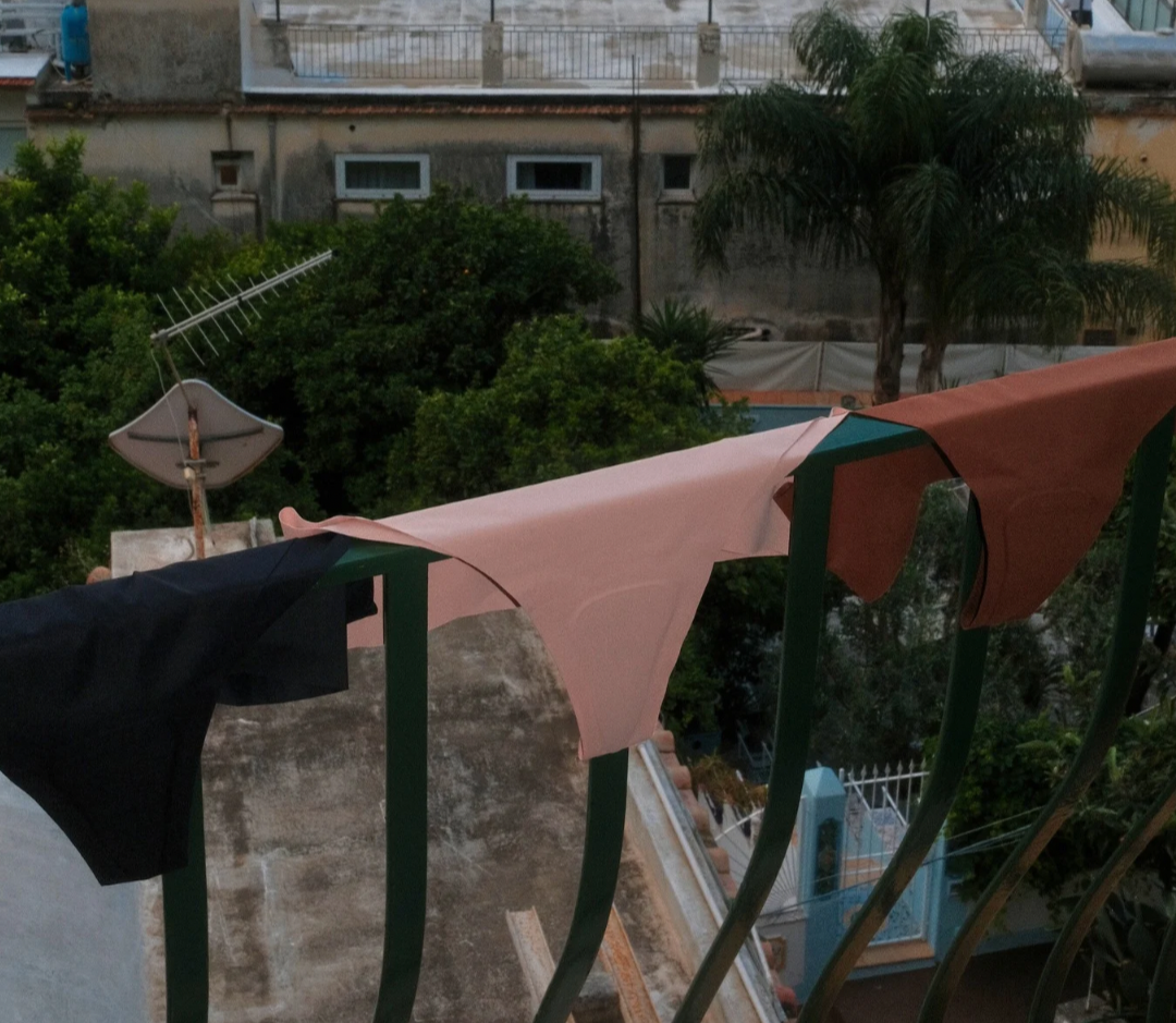 Breathable, lightweight camel toe concealing underwear hanging on a balcony railing—black, beige pink, and brown colors shown drying outdoors, highlighting quick-dry, sweat-wicking fabric.